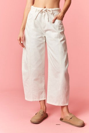 Person wearing white pants and beige shoes on a pink background