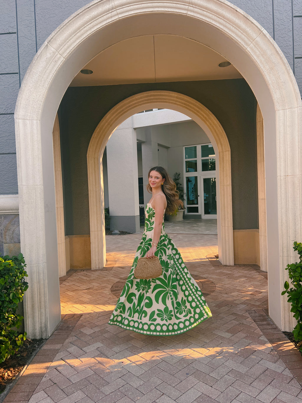 Woman in a green dress standing in front of an archway with a blurred background