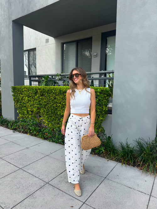 Woman standing outdoors near a building with greenery
